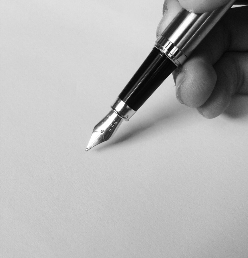 pexels-photo-753695-753695 A close-up of a fountain pen writing on blank paper in black and white, capturing elegance.